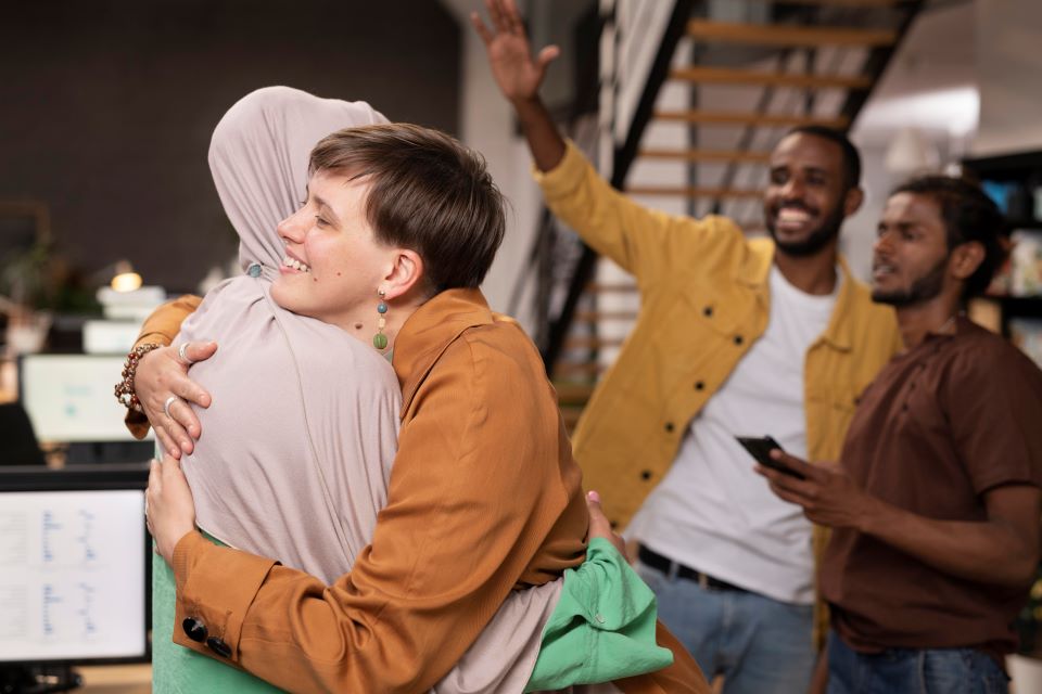 parsnip in ELT. a woman with a headscarf and a woman with short-cut hair hugging each other. 